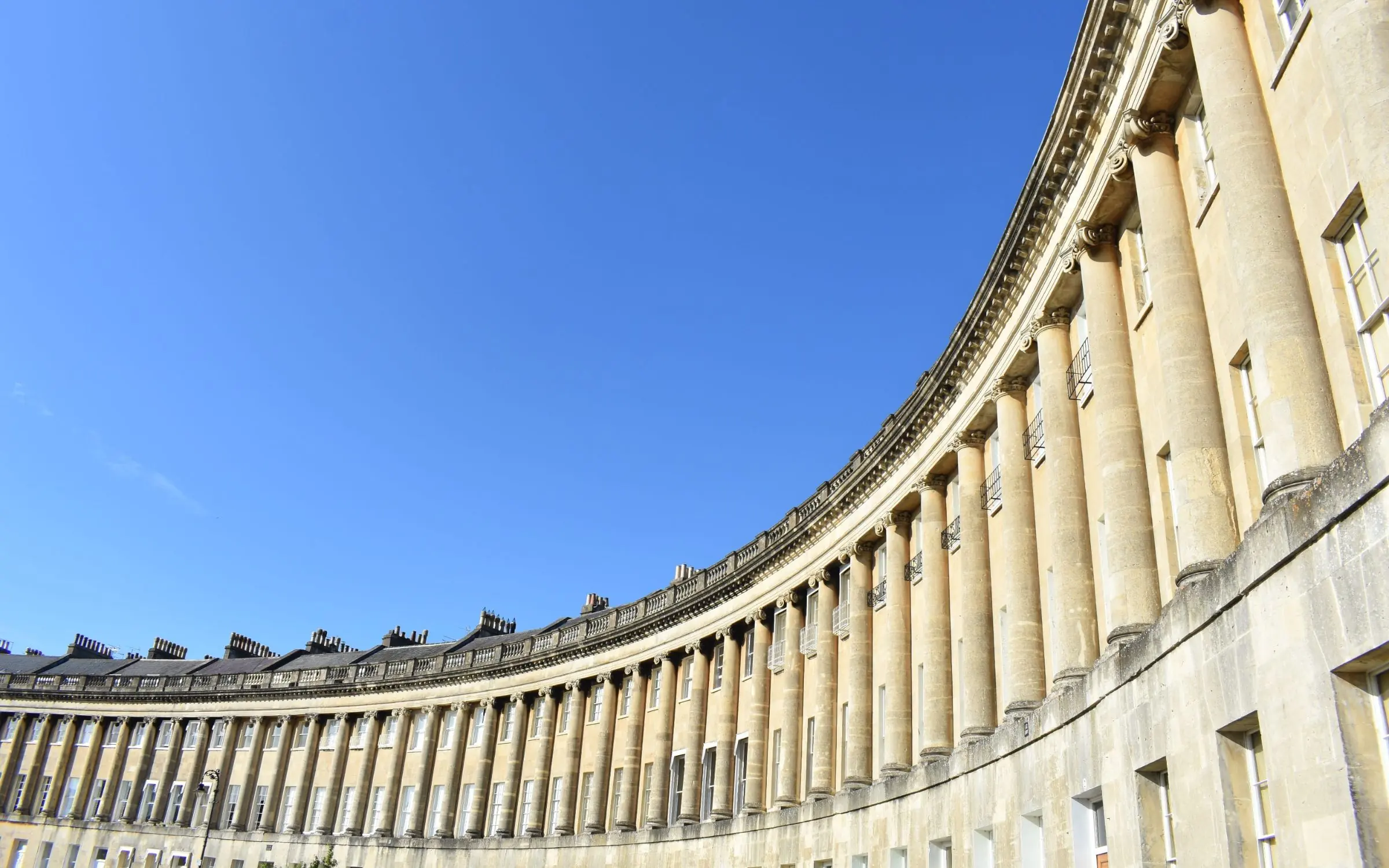 The Royal Crescent in Bath, its curved Georgian terrace against a clear blue sky