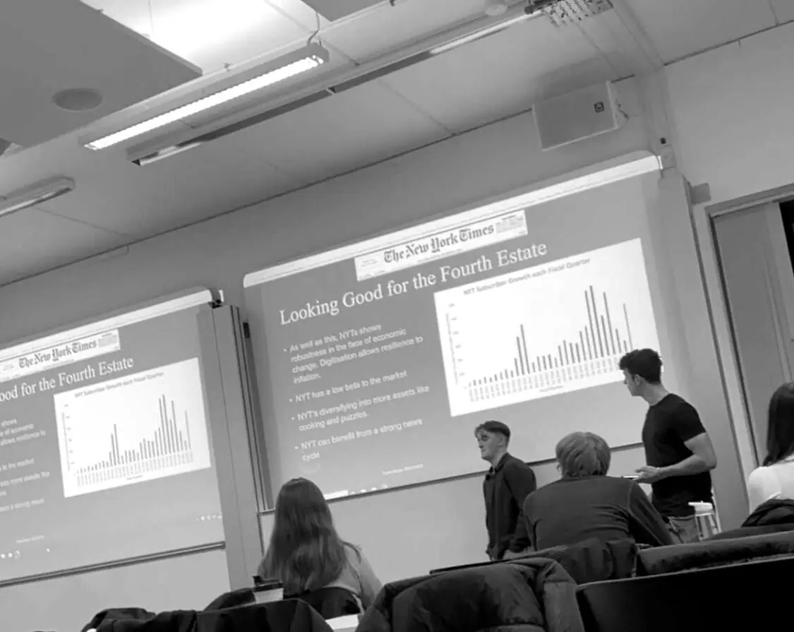 Black and white photo of members presenting a research slide with a bar chart